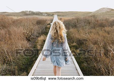 Young woman strolling on coastal dune boardwalk, rear view, Menemsha, Martha's Vineyard, Massachusetts, USA View Large Photo Image Stock Photograph - Young woman strolling on coastal dune boardwalk, rear view, Menemsha, Martha's Vineyard, Massachusetts, USA. Fotosearch