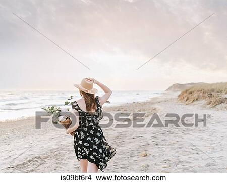 Young woman strolling with bunch of flowers on windy beach, rear view, Menemsha, Martha's Vineyard, Massachusetts, USA View Large Photo Image Picture - Young woman strolling with bunch of flowers on windy beach, rear view, Menemsha, Martha's Vineyard, Massachusetts, USA. Fotosearch