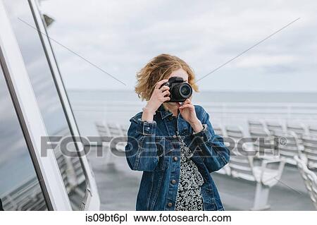 Stock Image - Young woman taking photographs on pier, Menemsha, Martha's Vineyard, Massachusetts, USA. Fotosearch