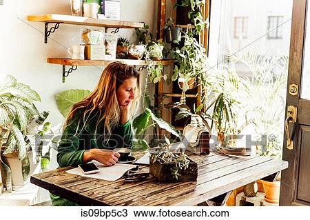 Stock Image - Young woman using laptop in cafe. Fotosearch
