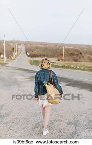 Picture - Young woman walking toward rural road, rear view, Menemsha, Martha's Vineyard, Massachusetts, USA. Fotosearch