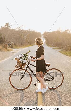 Young woman with bicycle looking sideways on rural road, Menemsha, Martha's Vineyard, Massachusetts, USA View Large Photo Image Stock Photo - Young woman with bicycle looking sideways on rural road, Menemsha, Martha's Vineyard, Massachusetts, USA. Fotosearch