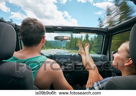 Stock Image - Young woman with feet up driving on road trip with boyfriend, Breckenridge, Colorado, USA. Fotosearch
