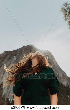 Young woman with flyaway hair looking up in front of sunlit mountain, Yosemite Village, California, USA View Large Photo Image Stock Photograph - Young woman with flyaway hair looking up in front of sunlit mountain, Yosemite Village, California, USA. Fotosearch