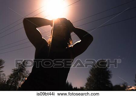 Young woman with hands on head against sunlit sky, backlit low angle view View Large Photo Image Stock Image - Young woman with hands on head against sunlit sky, backlit low angle view. Fotosearch