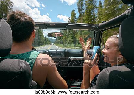 Stock Image - Young woman with instant camera driving on road trip with boyfriend, Breckenridge, Colorado, USA. Fotosearch