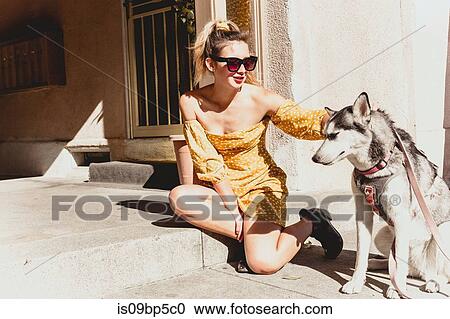 Stock Image - Young woman with pet dog on steps. Fotosearch