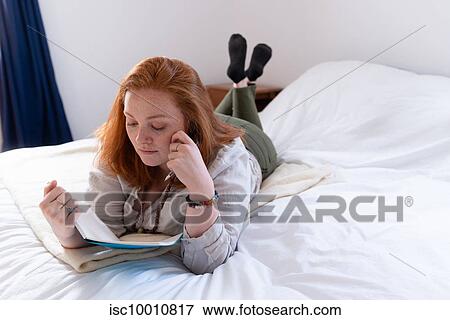 Young woman with red hair lying on bed reading her diary View Large Photo Image Stock Photo - Young woman with red hair lying on bed reading her diary. Fotosearch