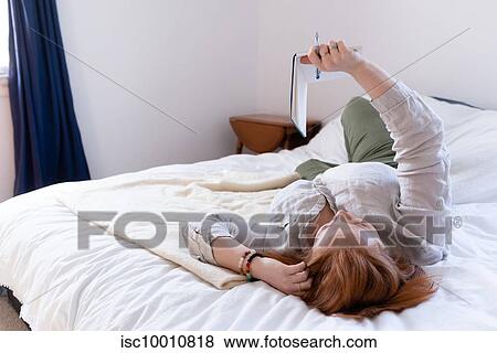 Young woman with red hair reclining on bed reading her diary View Large Photo Image Stock Photo - Young woman with red hair reclining on bed reading her diary. Fotosearch