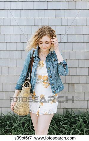 Young woman with straw bag in front of wall View Large Photo Image Stock Photo - Young woman with straw bag in front of wall. Fotosearch