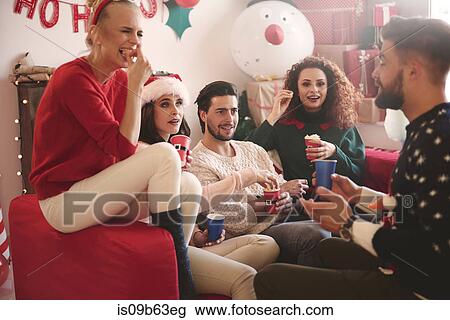 Young women and men eating popcorn on sofa at christmas party View Large Photo Image Stock Image - Young women and men eating popcorn on sofa at christmas party. Fotosearch
