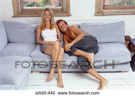 Couple sitting together on sofa View Large Photo Image Stock Photography - Couple sitting together on sofa. Fotosearch