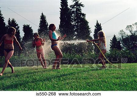Girls playing with a hosepipe View Large Photo Image Stock Photo - Girls playing with a hosepipe. Fotosearch