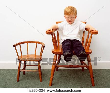 Picture - Young boy sitting on big chair. Fotosearch