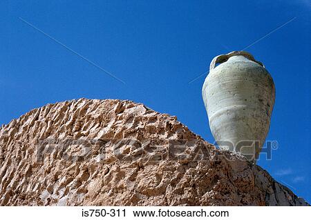 Stock Image - Urn on clay wall. Fotosearch
