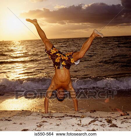 Picture - Man doing handstands on beach. Fotosearch