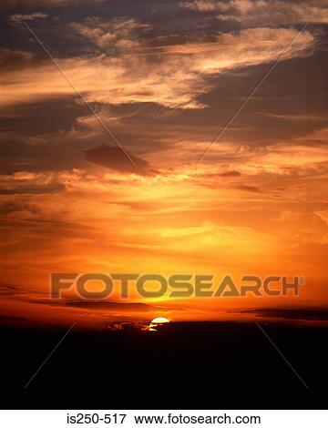 Stock Photo - Sunset over cloudy sky. Fotosearch