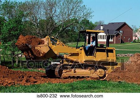 Stock Image - Builder using digger in garden. Fotosearch