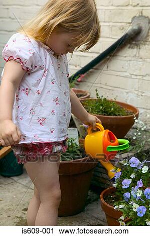 Girl watering plants in garden View Large Photo Image Stock Image - Girl watering plants in garden. Fotosearch