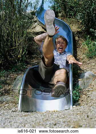 Stock Image - Excited man comes down slide.. Fotosearch