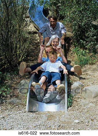 Stock Image - Family enjoy going on a slide.. Fotosearch