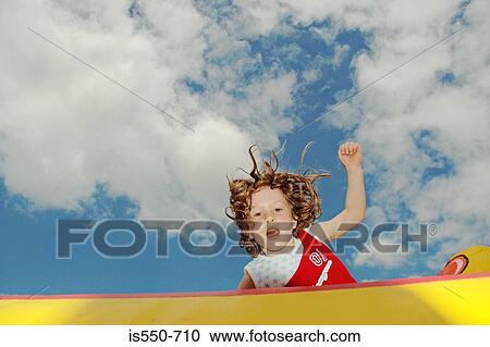 Stock Image - Girl jumping on bouncy castle. Fotosearch