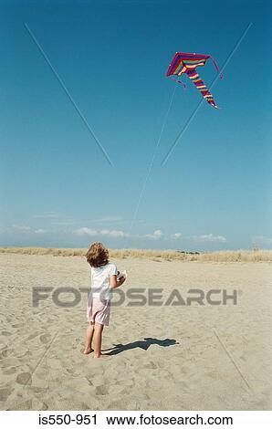 Stock Image - Child flying kite on the beach. Fotosearch