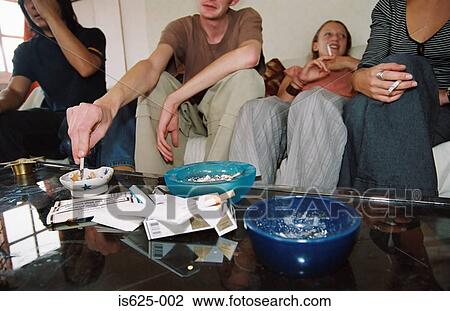 Stock Image - Friends smoking in living room. Fotosearch