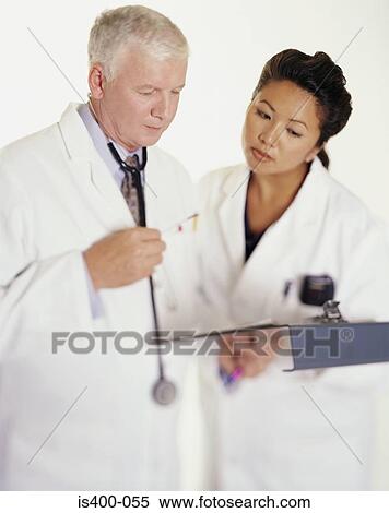 Stock Photography - Two doctors examining clipboard. Fotosearch