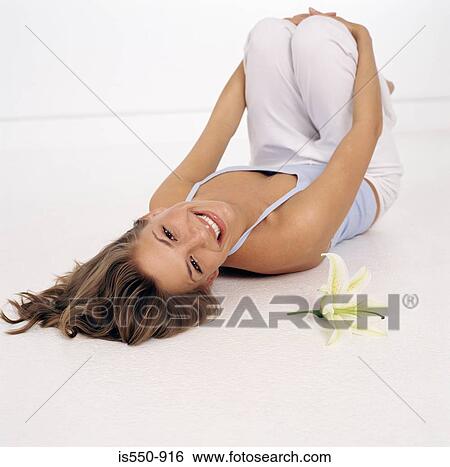 Stock Photograph - Young woman lying on her back with lily . Fotosearch