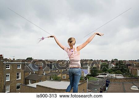 Stock Image - Angel standing on a roof. Fotosearch