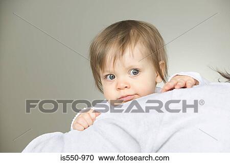 Stock Image - Baby peeping over a cushion. Fotosearch