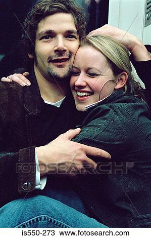 Stock Image - Couple hugging on subway train. Fotosearch
