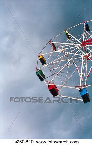 Stock Image - Ferris wheel and cloudy sky. Fotosearch