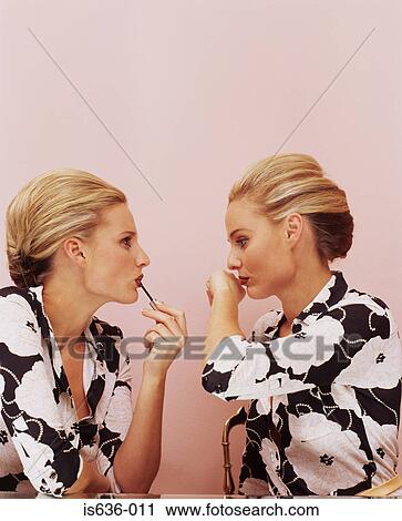 Stock Image - Two women applying lipstick. Fotosearch