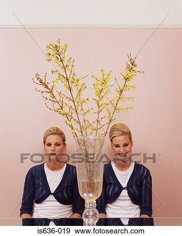 Two women sitting at table with a vase View Large Photo Image Stock Photo - Two women sitting at table with a vase. Fotosearch