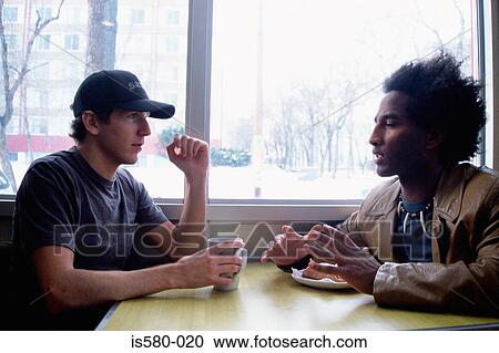 Two young men at a table View Large Photo Image Stock Image - Two young men at a table. Fotosearch