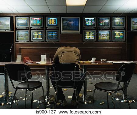 Stock Photo - Man slumped at table in betting shop. Fotosearch