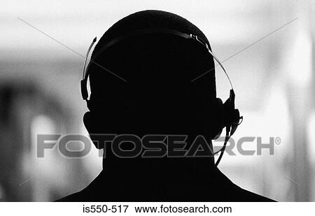 Silhouetted man wearing a telephone headset View Large Photo Image Stock Photo - Silhouetted man wearing a telephone headset. Fotosearch