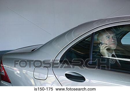 Stock Photography - Businessman in a car using mobile phone. Fotosearch