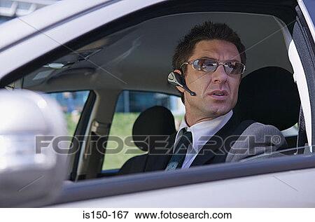 Stock Photo - Businessman in car wearing headset. Fotosearch