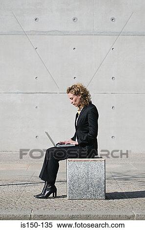 Stock Photography - Businesswoman sitting outdoors using a laptop. Fotosearch