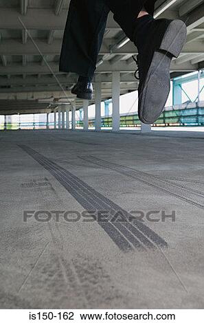 Stock Image - Man jumping in car park. Fotosearch