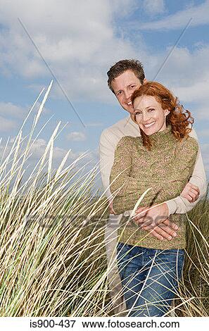 Couple hugging in a field View Large Photo Image Stock Photo - Couple hugging in a field. Fotosearch