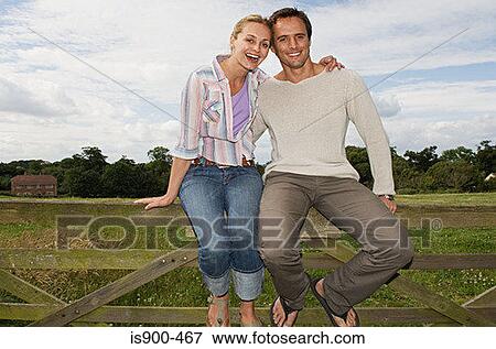 Couple sitting on a fence View Large Photo Image Stock Photo - Couple sitting on a fence. Fotosearch