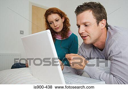 Stock Photo - Couple using laptop computer in bedroom. Fotosearch
