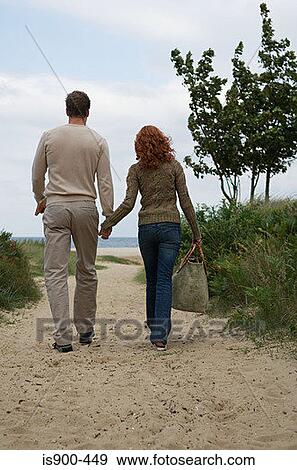 Stock Photo - Couple walking toward sandy beach. Fotosearch