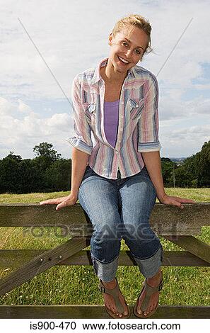 Woman sitting on a fence View Large Photo Image Stock Image - Woman sitting on a fence. Fotosearch