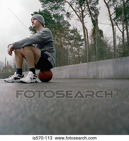 Young man sitting on a basketball View Large Photo Image Stock Image - Young man sitting on a basketball. Fotosearch