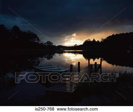Stock Photo - Boat by pier at sunset. Fotosearch